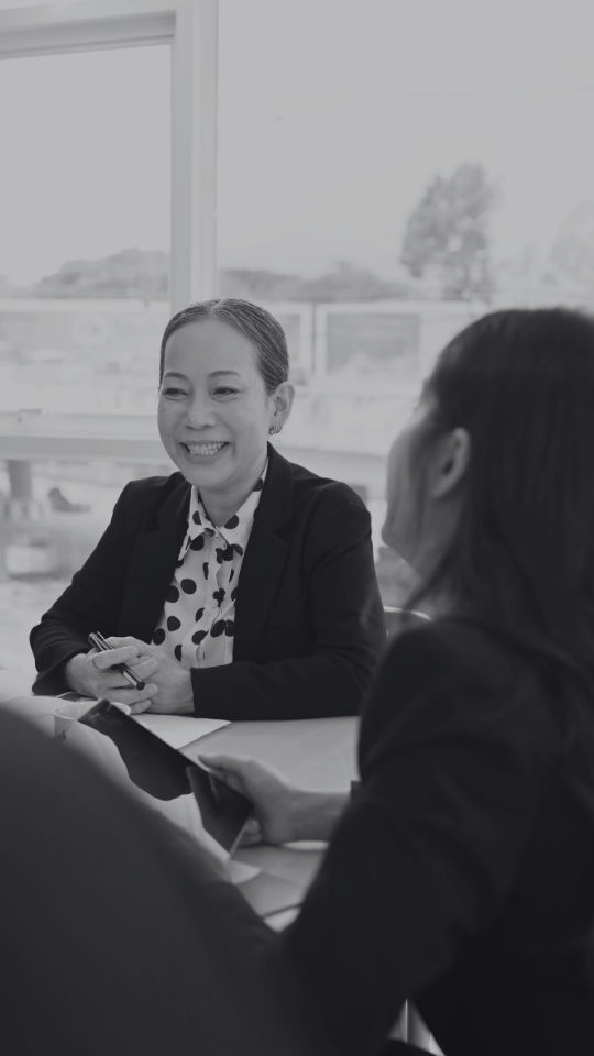 Smiling asian corporate woman sitting at meeting table